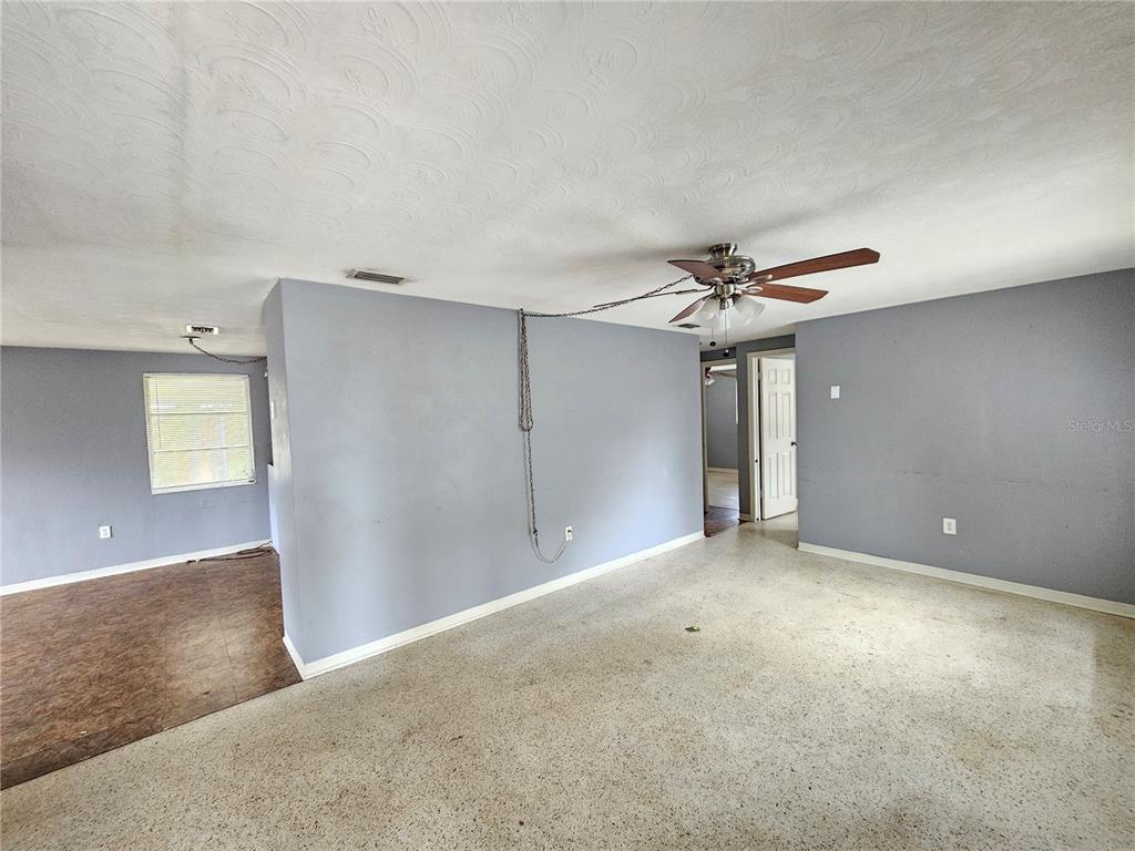 A living room features gray walls, a ceiling fan with a chain, and terrazzo flooring — 1702 AQUA LANE, HOLIDAY, FL