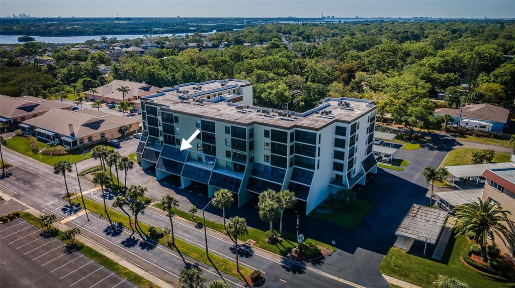 An aerial view of a multi-story apartment building with a white arrow pointing to a balcony — 9860 62ND TERRACE N UNIT 1025, ST PETERSBURG, FL