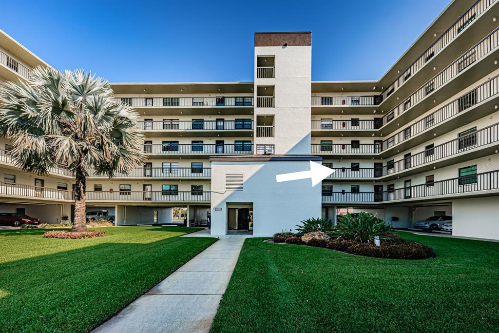 A multi-story apartment building with balconies and a central walkway leading to the entrance — 9860 62ND TERRACE N UNIT 1025, ST PETERSBURG, FL