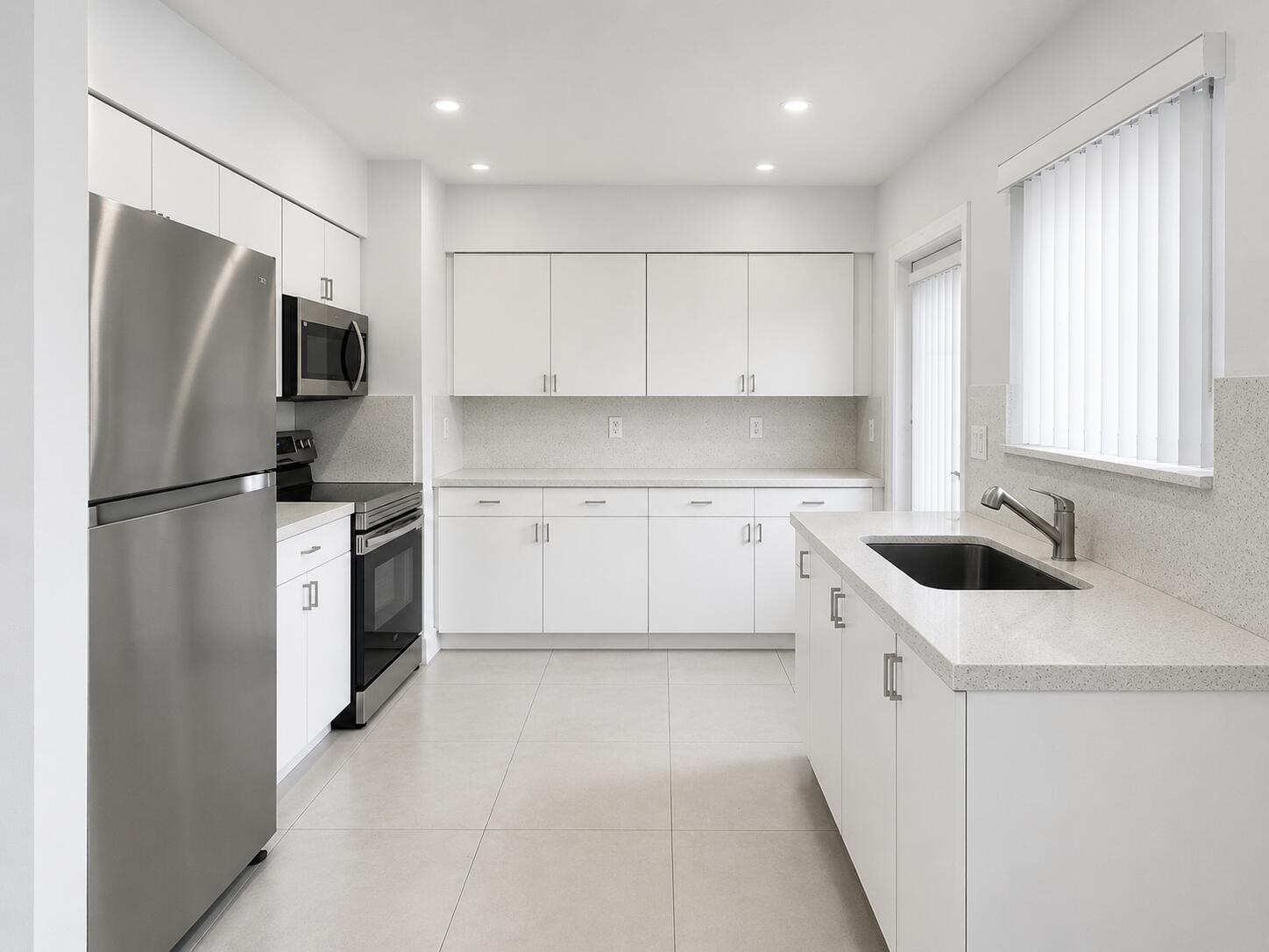 A modern white kitchen features stainless steel appliances, light countertops, and large floor tiles — 2152 SW 72nd Avenue, Miami FL 33155, MIAMI, FL