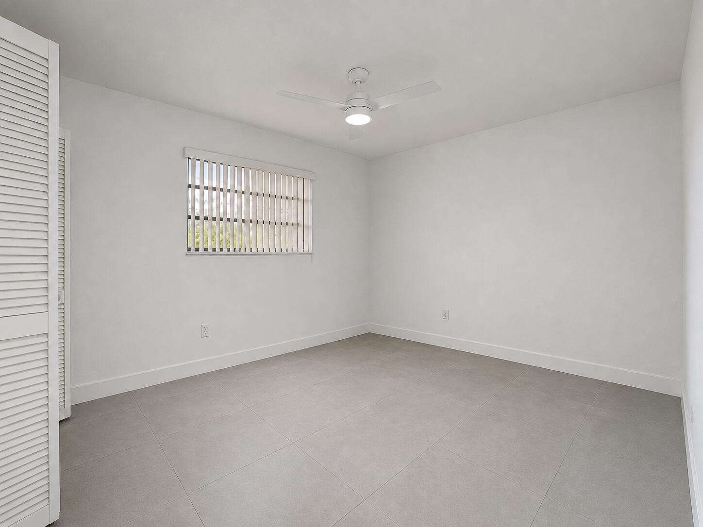 An empty bedroom features white walls, gray tile flooring, a ceiling fan, and louvered closet doors — 2152 SW 72nd Avenue, Miami FL 33155, MIAMI, FL