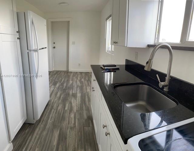 A kitchen features white cabinets, a black countertop, a stainless steel sink, and wood-look flooring — 337 NW 59th Ter # A, Miami FL 33127, MIAMI, FL