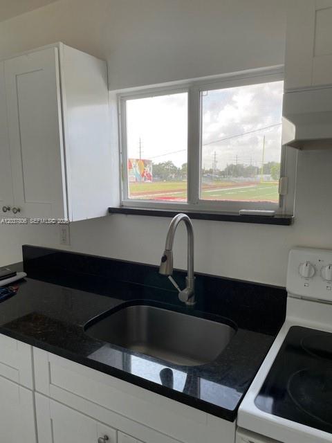 A kitchen features white cabinets, a black countertop, a stainless steel sink, and a window — 337 NW 59th Ter # A, Miami FL 33127, MIAMI, FL