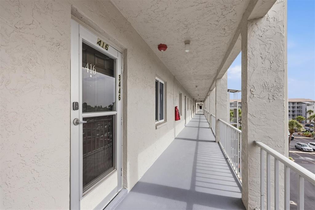 An exterior walkway with a white door, concrete flooring, and a metal railing — 3446 LAKE BAYSHORE DRIVE UNIT 416, BRADENTON, FL