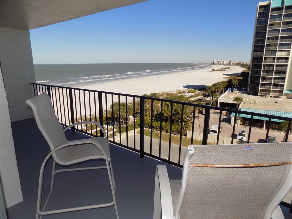 A balcony with two chairs overlooks a sandy beach and the ocean — 1400 GULF BOULEVARD UNIT 608, CLEARWATER BEACH, FL