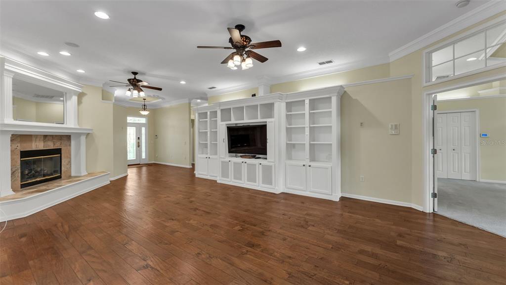 A living room features hardwood floors, a fireplace, built-in shelving, and two ceiling fans — 6540 LAKE CLARK DRIVE, LAKELAND, FL