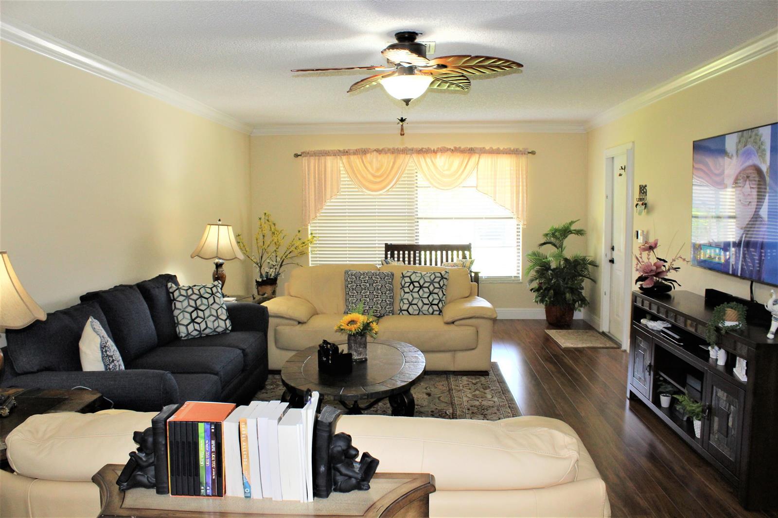 A living room features a dark sofa, a beige sofa, wood flooring, and a ceiling fan — 9940 Bauhinia Tree Way # B, Boynton Beach FL 33436, BOYNTON BEACH, FL