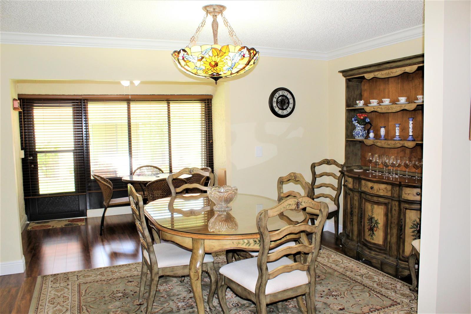 A dining room features a glass-topped table, a hutch, and a stained-glass chandelier — 9940 Bauhinia Tree Way # B, Boynton Beach FL 33436, BOYNTON BEACH, FL