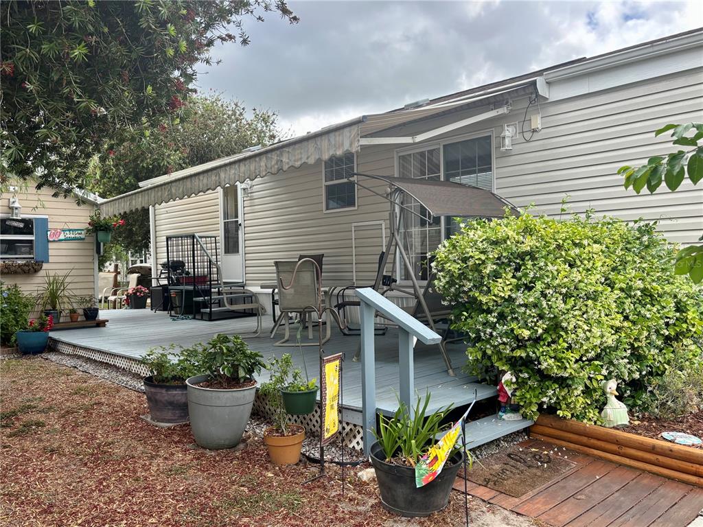 A mobile home features a large wooden deck with an awning and outdoor seating — 3255 NE 104TH AVENUE, SILVER SPRINGS, FL