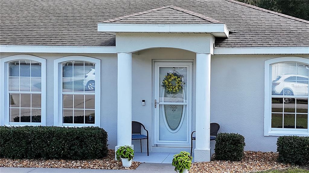 The exterior of a house features a covered entryway with two columns and a front door — 13777 SE 44TH AVENUE, SUMMERFIELD, FL