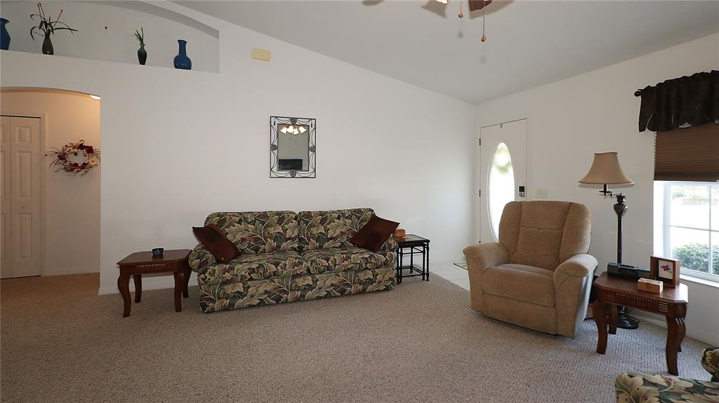 A living room features a floral sofa, a beige recliner, and a decorative wall niche — 13777 SE 44TH AVENUE, SUMMERFIELD, FL
