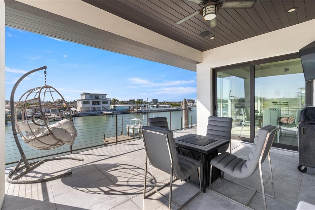 A covered patio features a hanging chair, dining set, and a view of the water — 7966 1ST AVENUE S, ST PETERSBURG, FL