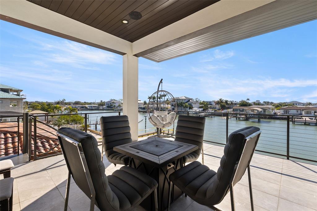 A covered balcony features a fire pit table with four chairs and a hanging chair — 7966 1ST AVENUE S, ST PETERSBURG, FL