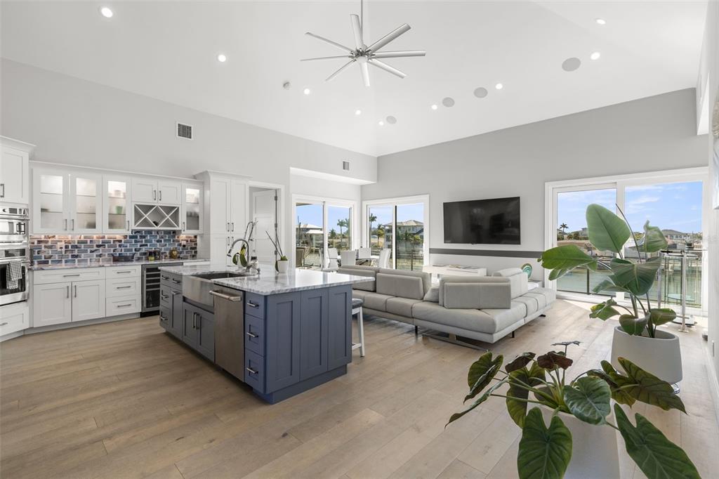 An open-concept kitchen and living area features a blue island, white cabinetry, and water views — 7966 1ST AVENUE S, ST PETERSBURG, FL