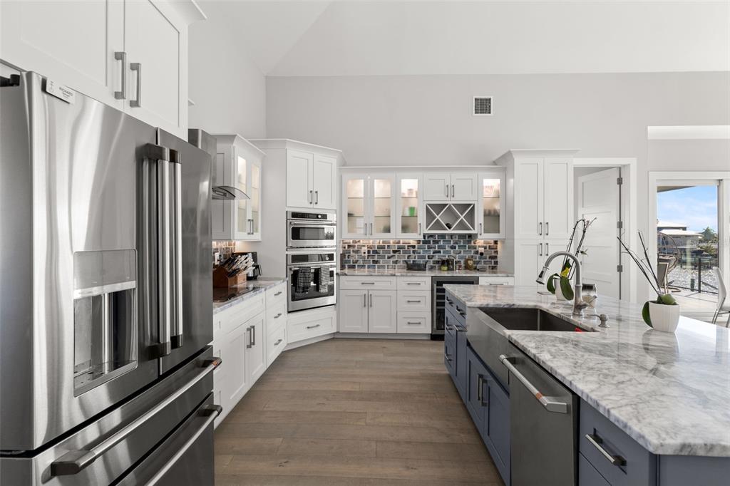 A modern kitchen features white cabinets, a blue island with a farmhouse sink, and stainless appliances — 7966 1ST AVENUE S, ST PETERSBURG, FL
