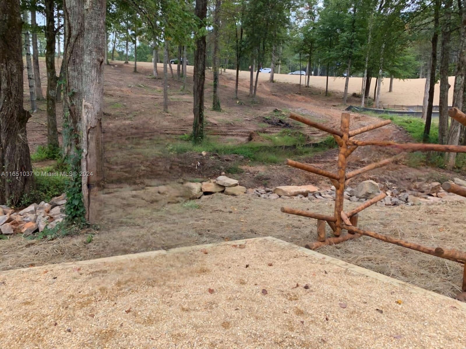 A wooden rack stands on a gravel patio overlooking a wooded area with cleared land — Yonah Lake Dr Lot 6, GA 30571, GA