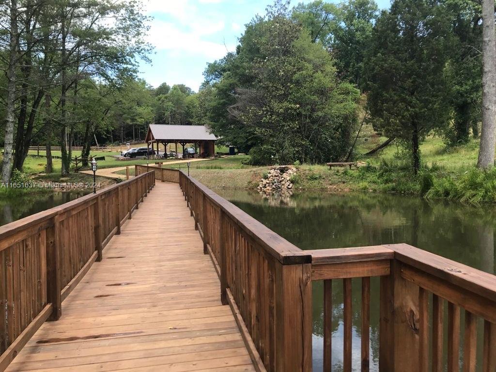A wooden footbridge extends over a pond toward a covered pavilion in a grassy area — Yonah Lake Dr Lot 6, GA 30571, GA