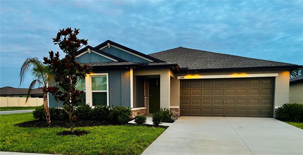 A single-story house with a blue-accented facade, a two-car garage, and a front lawn — 2141 LANIER ROAD, ZEPHYRHILLS, FL
