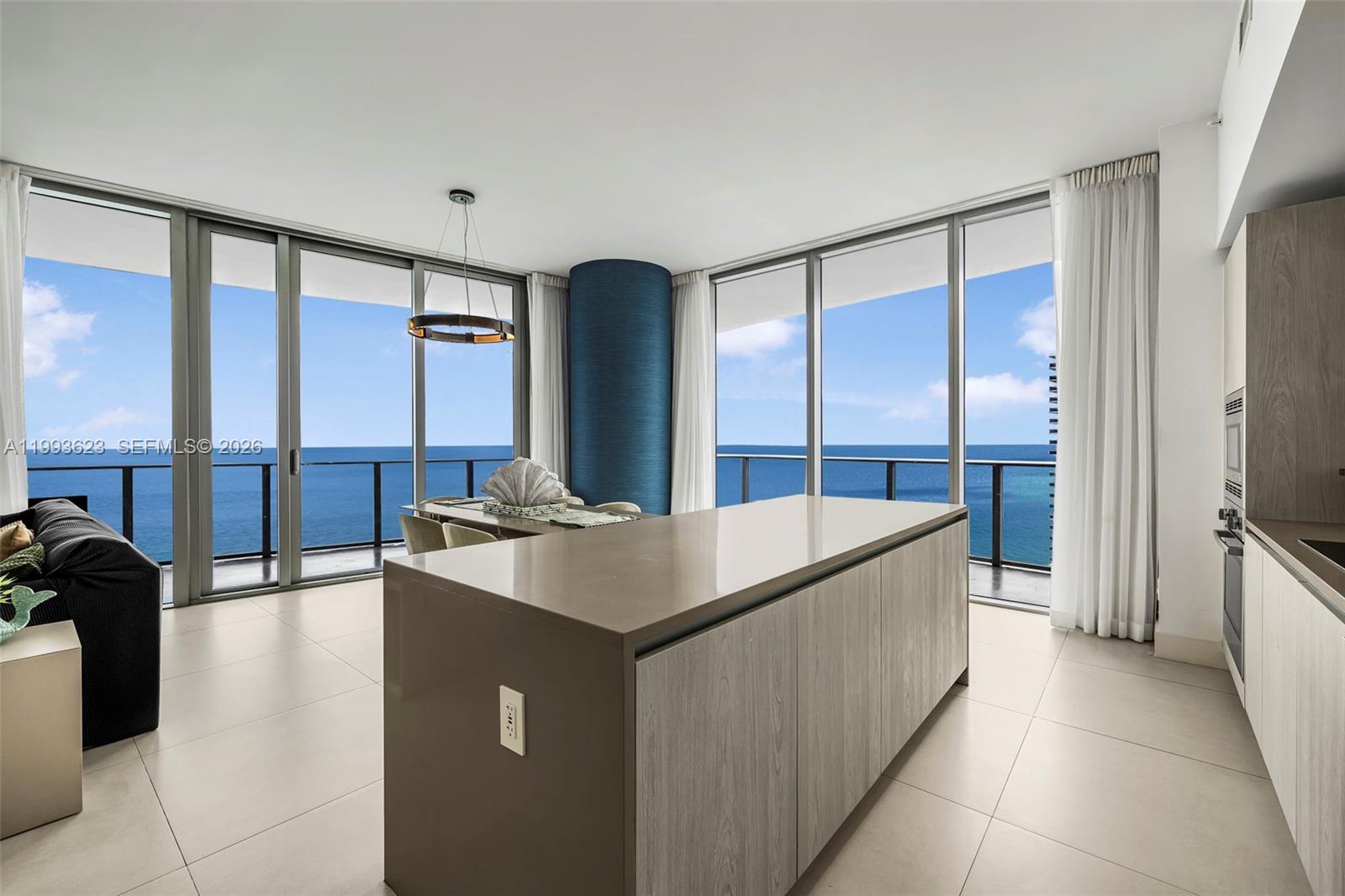 A modern kitchen and dining area features a large island, tile floors, and ocean views — 4111 S Ocean Dr, Hollywood FL 33019, HOLLYWOOD, FL