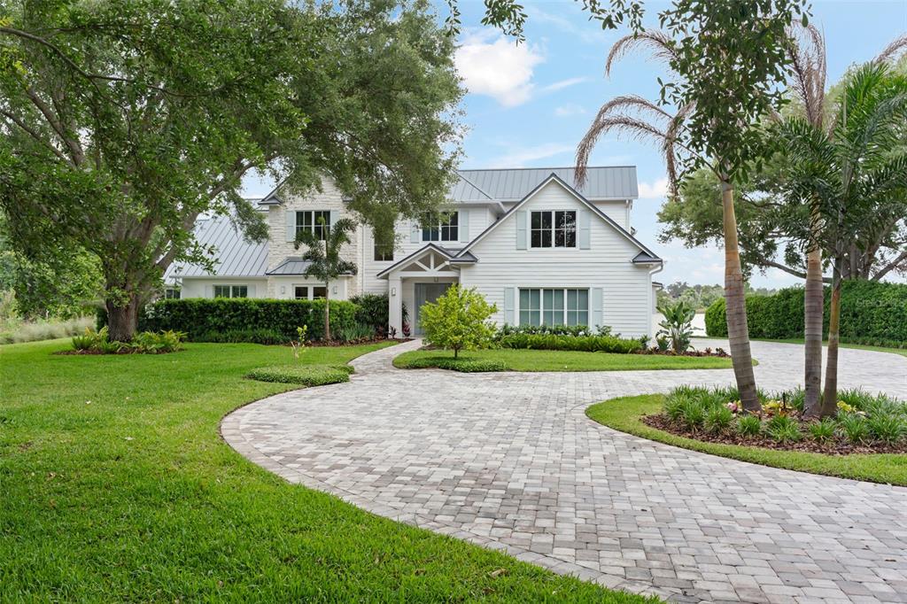 A white two-story house with a metal roof and a paved circular driveway — 13542 SUNSET LAKES CIRCLE, WINTER GARDEN, FL