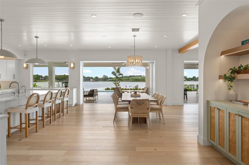 An open-concept kitchen and dining area features light wood floors and a view of water — 13542 SUNSET LAKES CIRCLE, WINTER GARDEN, FL