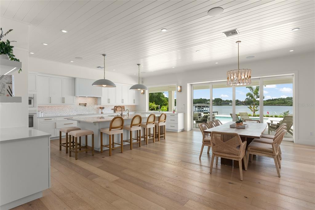 A bright kitchen and dining area with white cabinetry, a large island, and waterfront views — 13542 SUNSET LAKES CIRCLE, WINTER GARDEN, FL