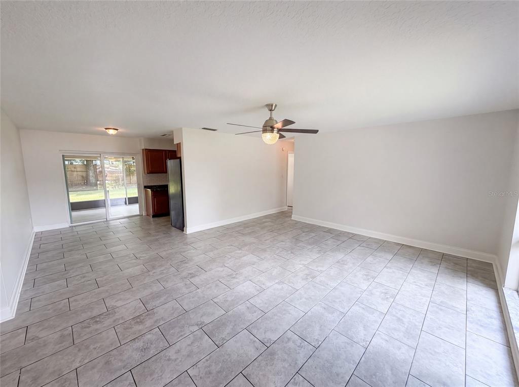An open-concept living area features gray tile flooring, a ceiling fan, and a sliding glass door — 7026 HAMMOCK WAY, WINTER PARK, FL