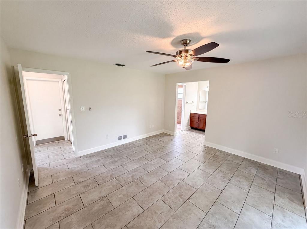 An empty room with light-colored walls, tile flooring, a ceiling fan, and two doorways — 7026 HAMMOCK WAY, WINTER PARK, FL