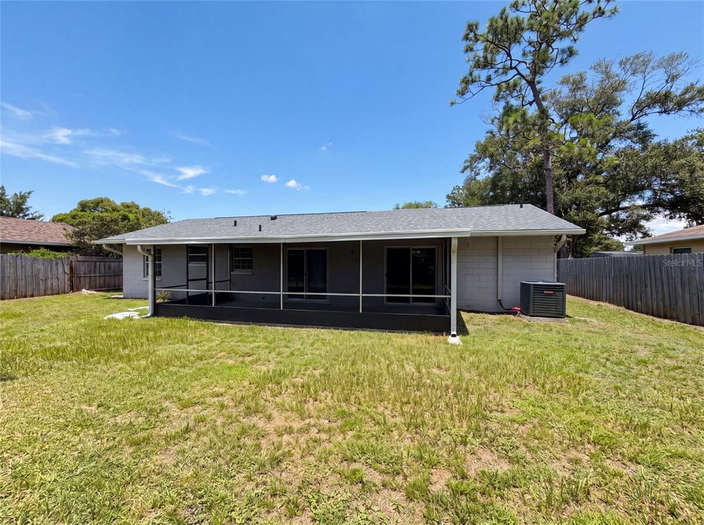The rear exterior of a single-story house features a screened-in porch and a grassy yard — 7026 HAMMOCK WAY, WINTER PARK, FL