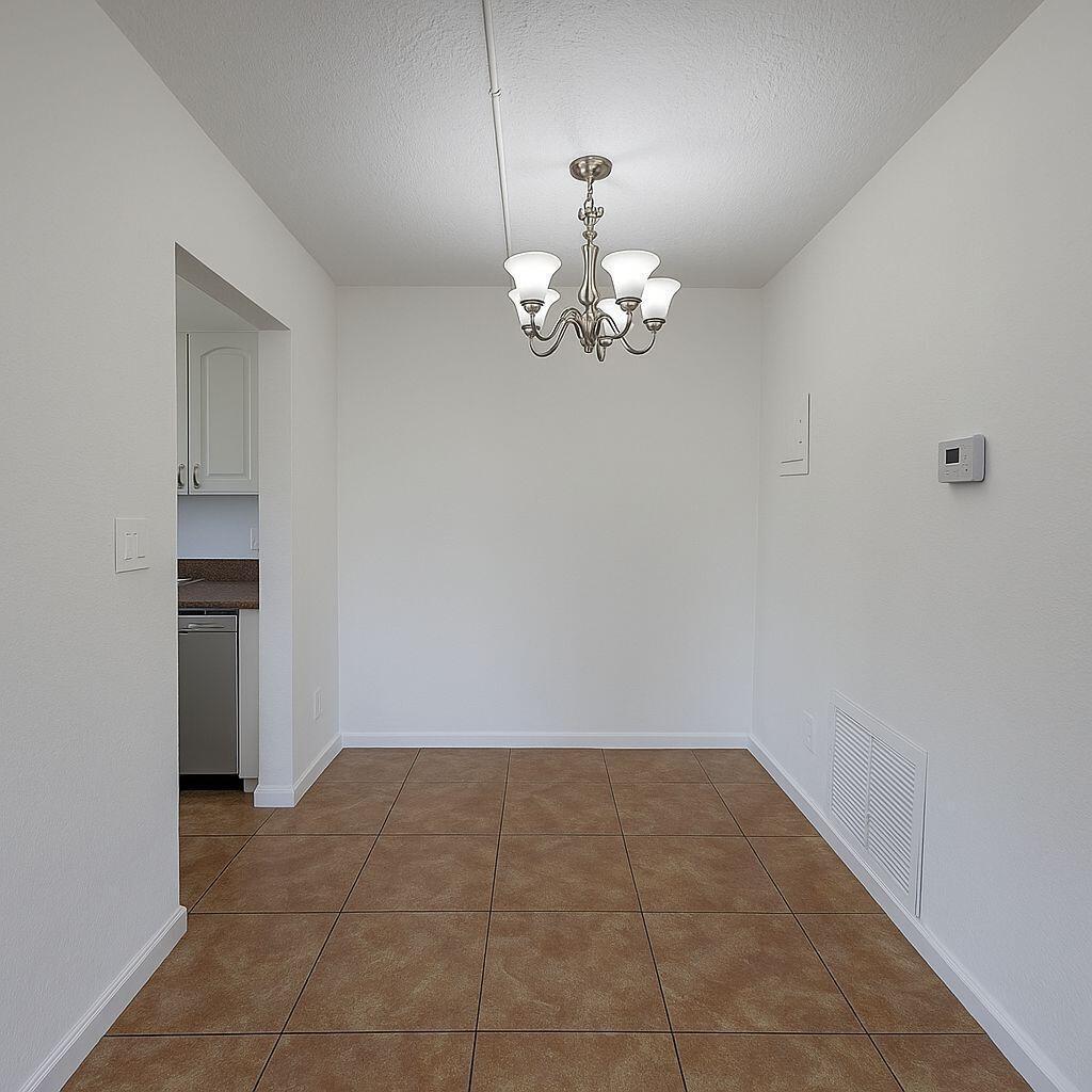 A dining area with tan tile flooring, a chandelier, and an adjacent kitchen doorway — 3390 NE 16th Terrace # 5, Pompano Beach FL 33064, POMPANO BEACH, FL