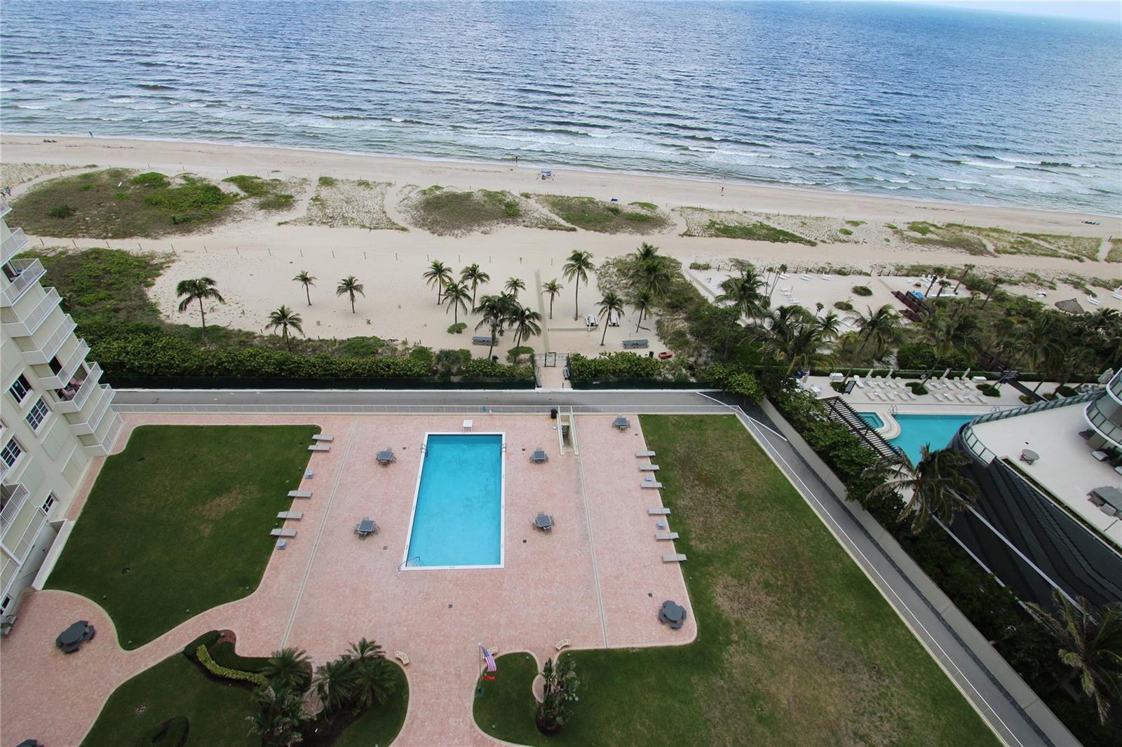 An aerial view shows a swimming pool, grassy lawn, and beach access at a coastal property — 750 N Ocean Boulevard # 1709, Pompano Beach FL 33062, POMPANO BEACH, FL