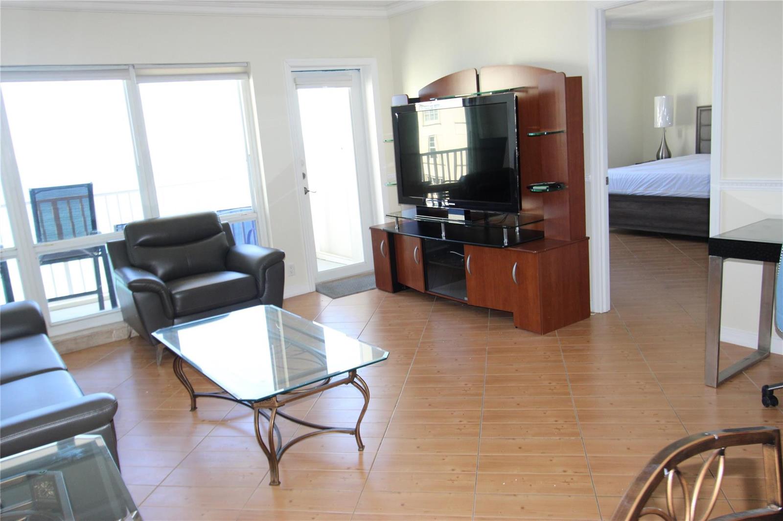 A living room with tile floors, a glass coffee table, leather seating, and a television console — 750 N Ocean Boulevard # 1709, Pompano Beach FL 33062, POMPANO BEACH, FL