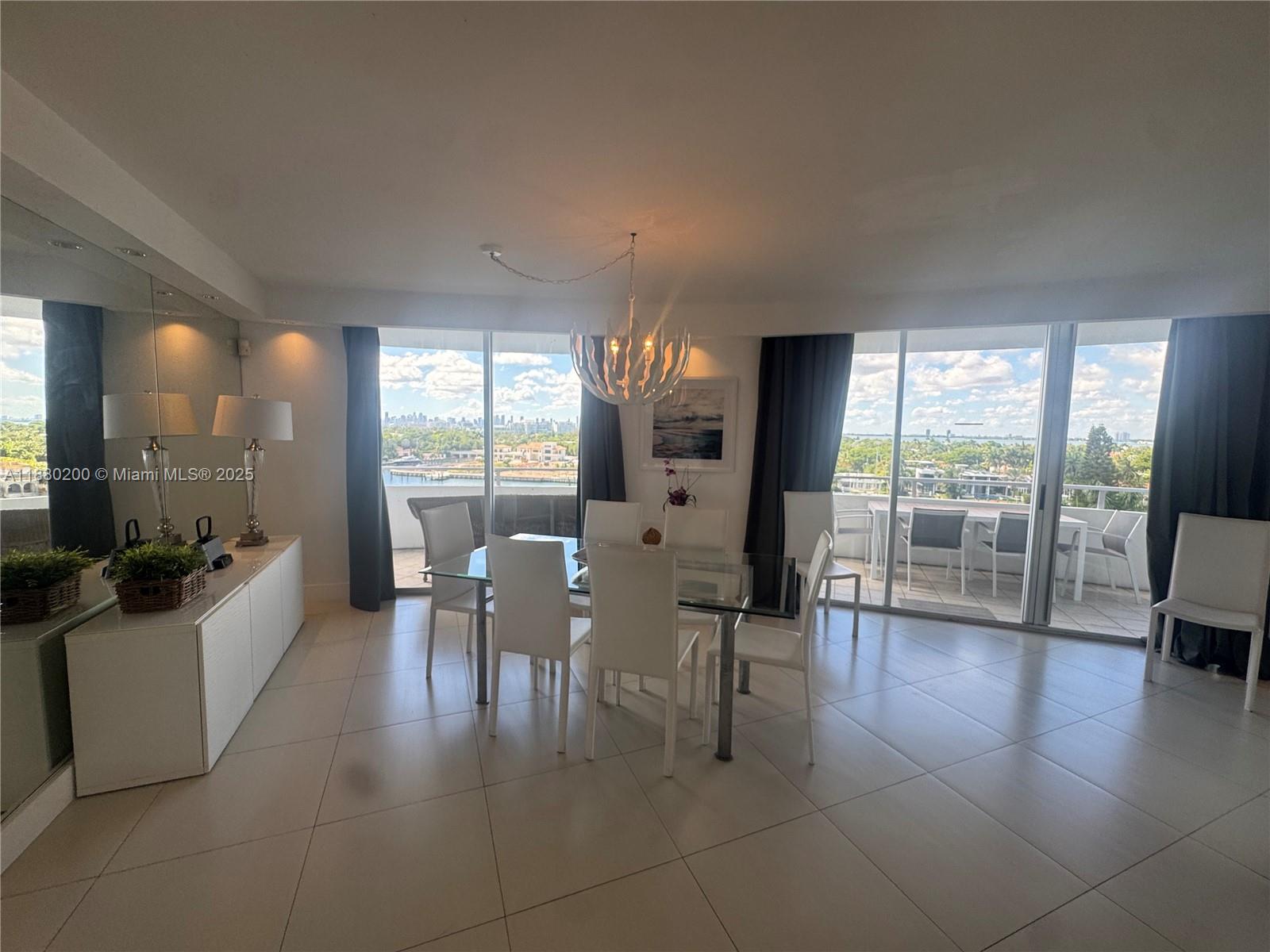 A dining room features a glass table, white chairs, tile floors, and floor-to-ceiling windows — 5151 Collins Ave # 923, Miami Beach FL 33140, MIAMI BEACH, FL