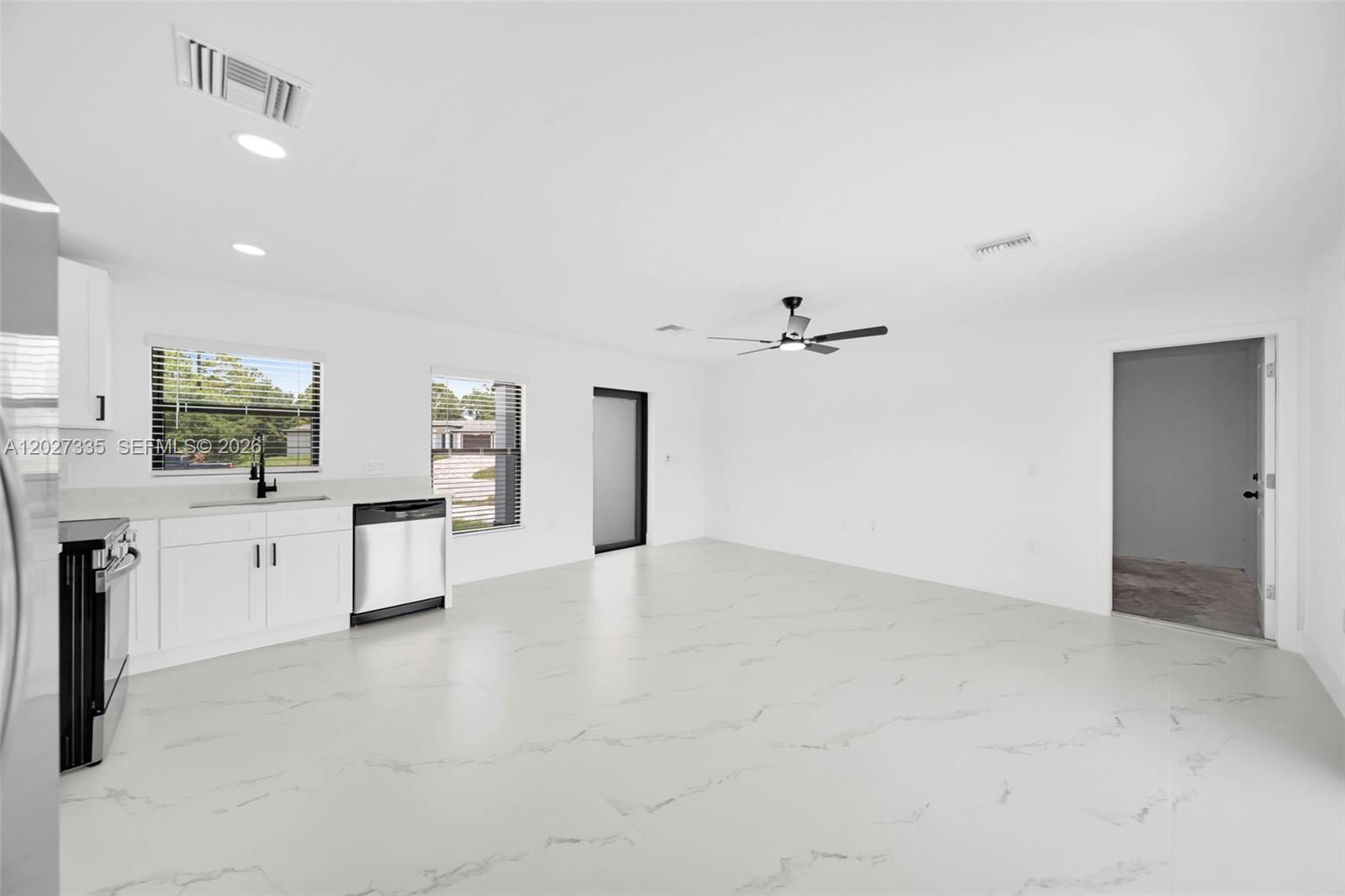 A modern, open-concept kitchen and living area features white cabinetry and marble-patterned tile flooring — 4985 Fairway Ct # 4985, Lehigh Acres FL 33971, LEHIGH ACRES, FL