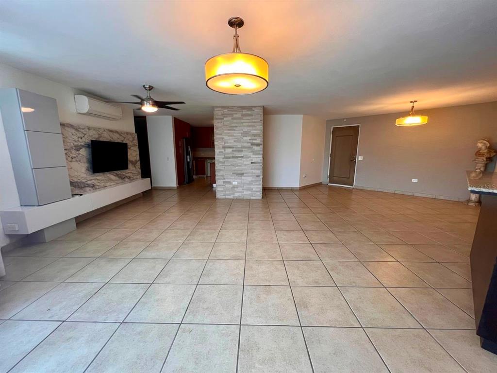 A spacious living area features tile flooring, a stone accent wall, and modern light fixtures — 675 SERGIO CUEVAS BUSTAMANTE UNIT 401, SAN JUAN, PR