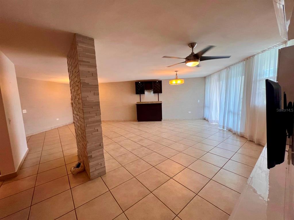 A spacious room features tiled floors, a stone-accented pillar, a ceiling fan, and a bar — 675 SERGIO CUEVAS BUSTAMANTE UNIT 401, SAN JUAN, PR