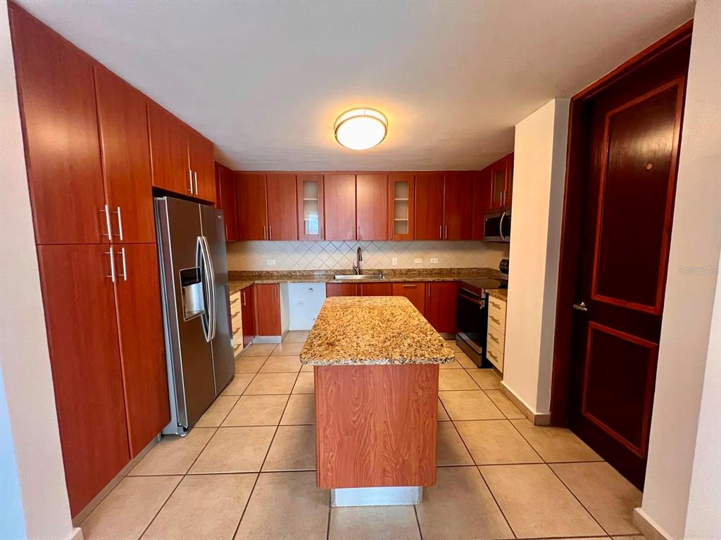 A kitchen features wood cabinets, granite countertops, a central island, and stainless steel appliances — 675 SERGIO CUEVAS BUSTAMANTE UNIT 401, SAN JUAN, PR