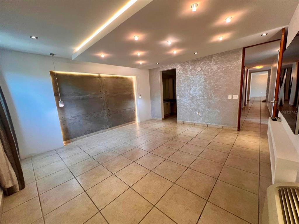 An empty room features large floor tiles, recessed ceiling lighting, and a textured accent wall — 675 SERGIO CUEVAS BUSTAMANTE UNIT 401, SAN JUAN, PR