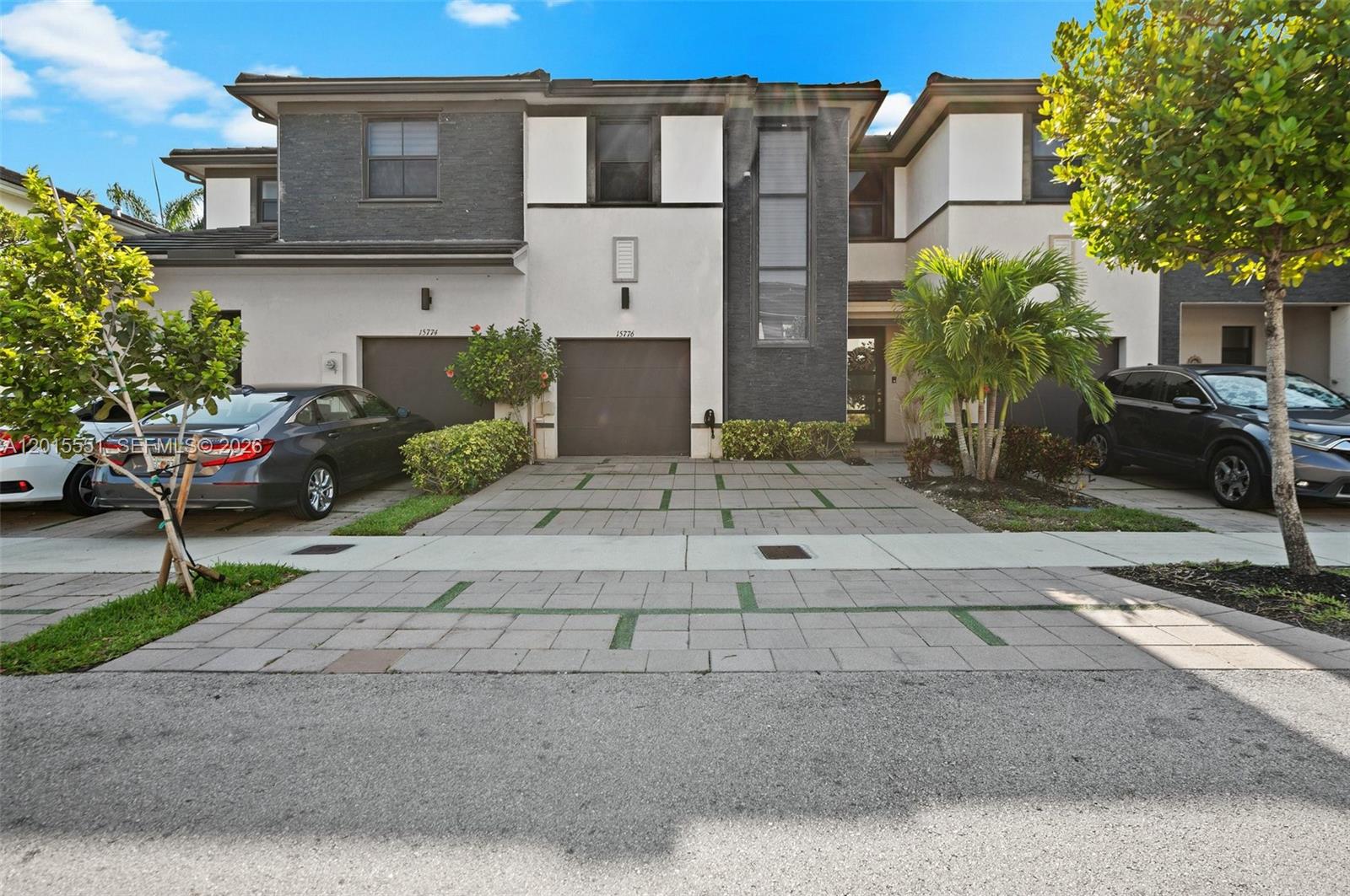 A two-story townhouse with a paved driveway, two garage doors, and modern exterior finishes — 15776 NW 91st Ct, Miami Lakes FL 33018, MIAMI LAKES, FL
