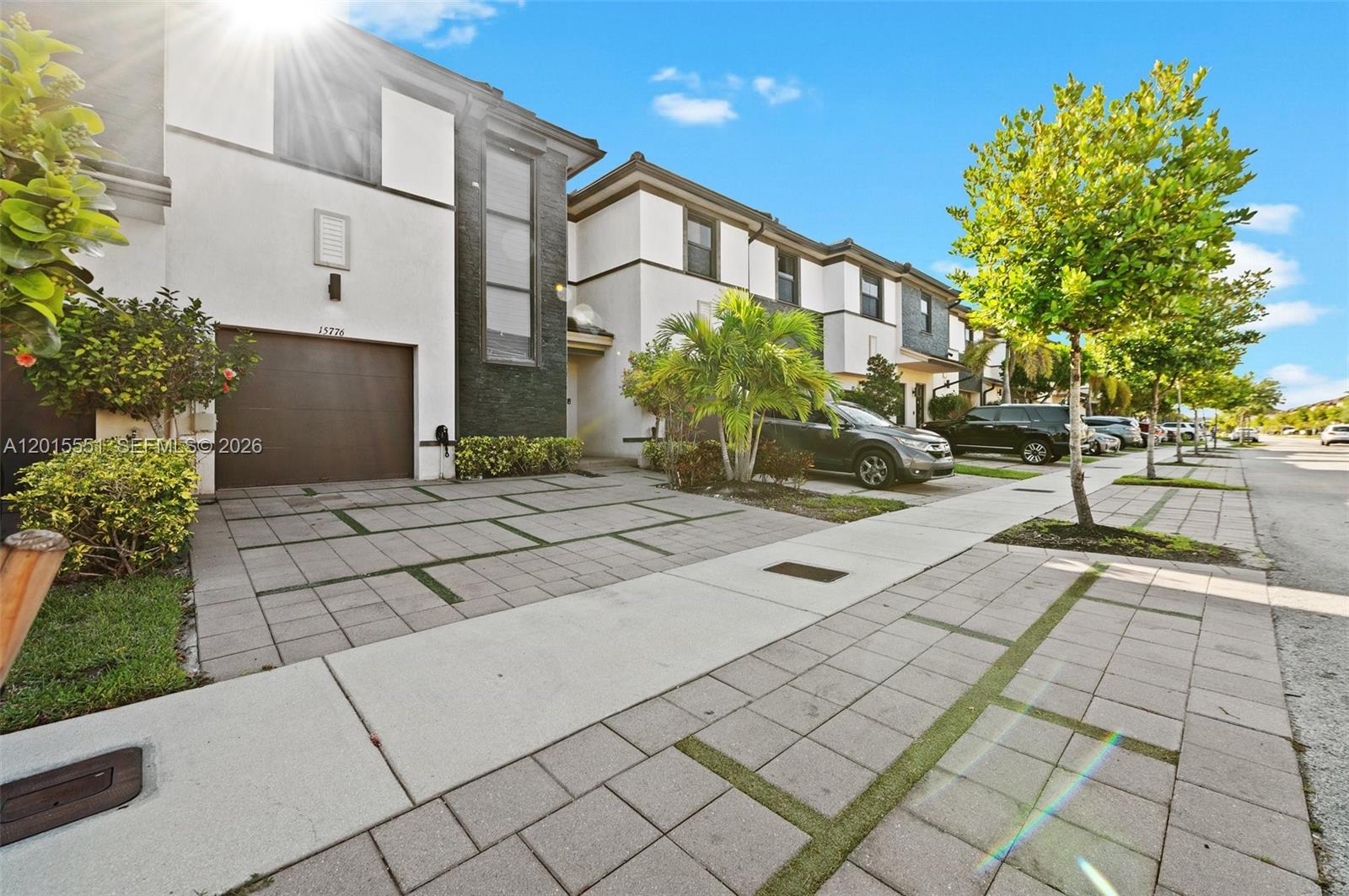 A modern townhome exterior features a paved driveway, a garage, and a sidewalk — 15776 NW 91st Ct, Miami Lakes FL 33018, MIAMI LAKES, FL