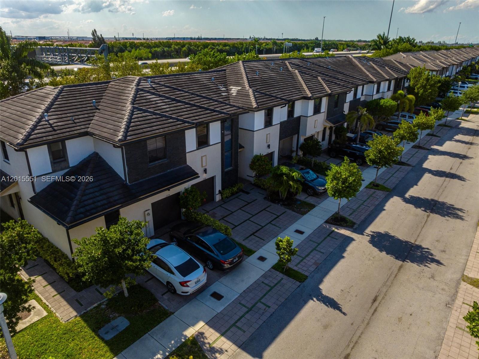 An aerial view shows a row of modern townhouses with driveways and parked cars — 15776 NW 91st Ct, Miami Lakes FL 33018, MIAMI LAKES, FL