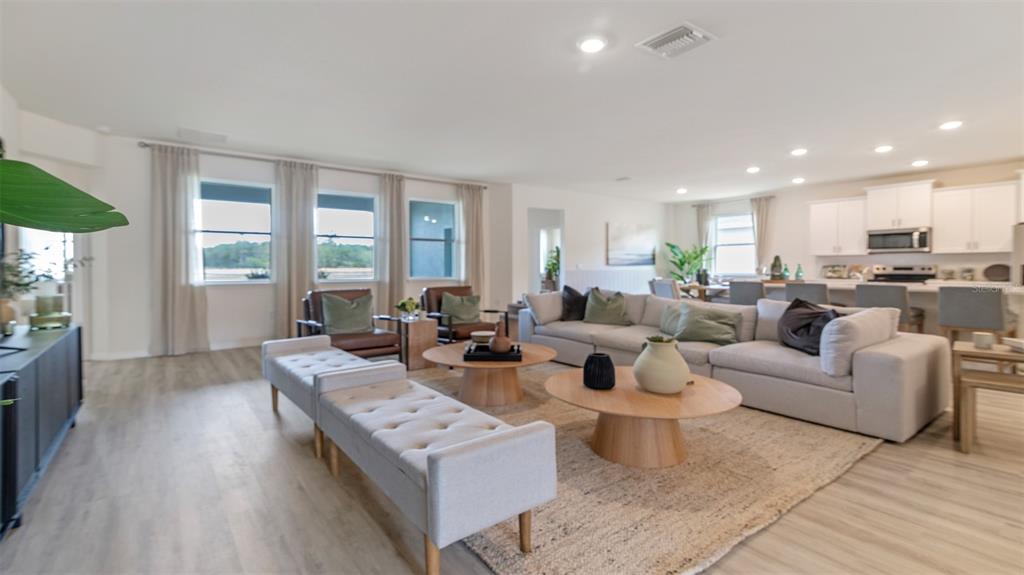 An open-concept living room features a large sectional sofa, two coffee tables, and a kitchen — 3001 KINGSMAN TRAIL, ORMOND BEACH, FL