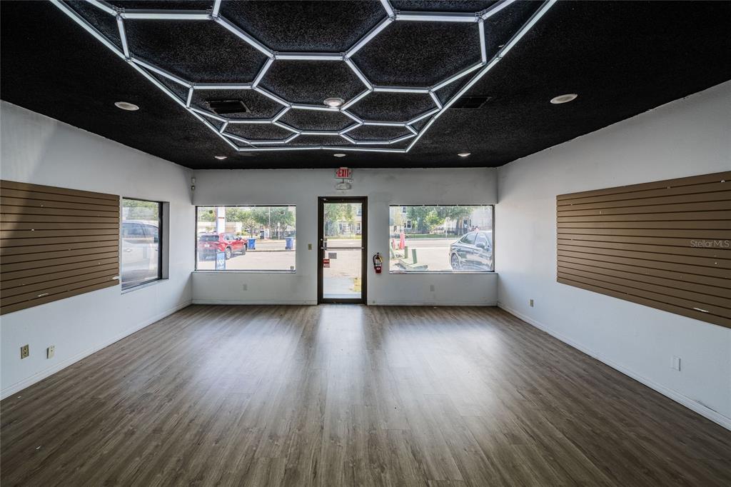 An empty commercial space features wood-look flooring, slat wall panels, and a hexagonal ceiling light — 211 E CENTRAL AVENUE, WINTER HAVEN, FL
