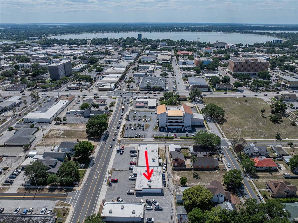 An aerial view shows a commercial building with a red arrow pointing to its roof — 211 E CENTRAL AVENUE, WINTER HAVEN, FL