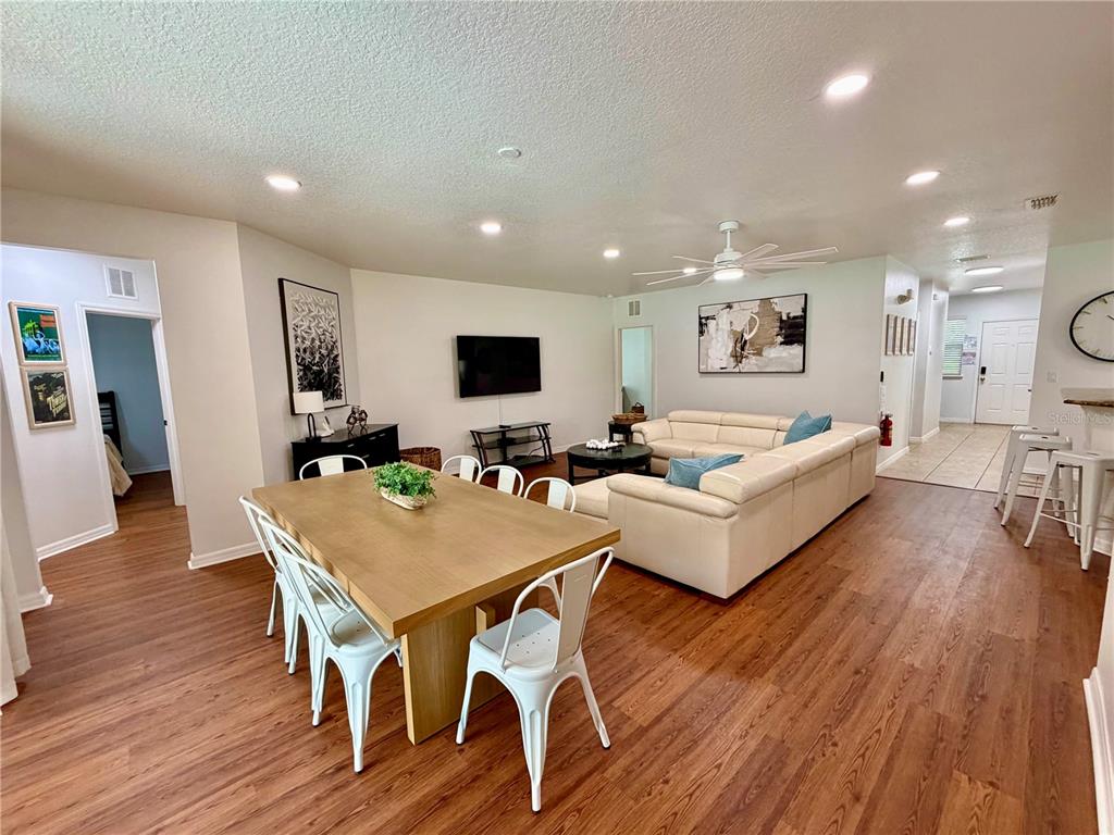 An open-concept living and dining area features wood-look flooring, a white sectional, and a table — 9110 STROMBOLI COURT, KISSIMMEE, FL