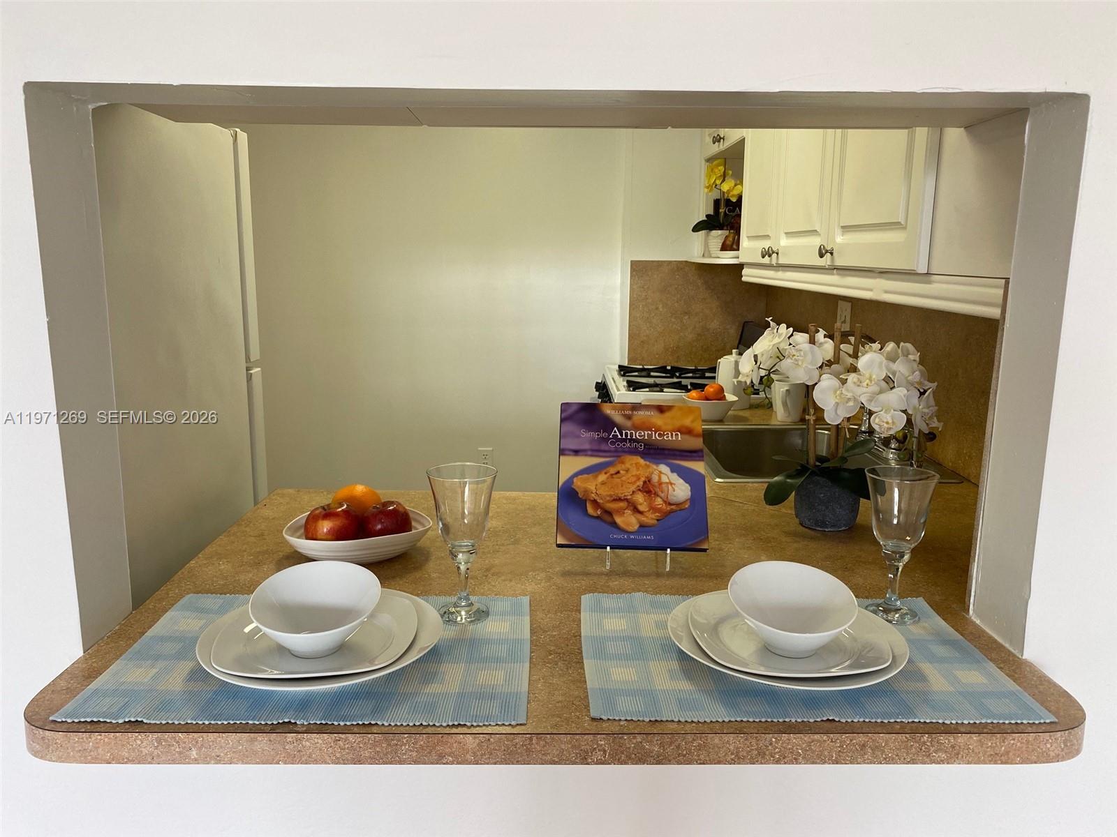A kitchen pass-through counter features two place settings, a cookbook, and a fruit bowl — 13120 SW 92nd Ave # 414, Miami FL 33176, MIAMI, FL