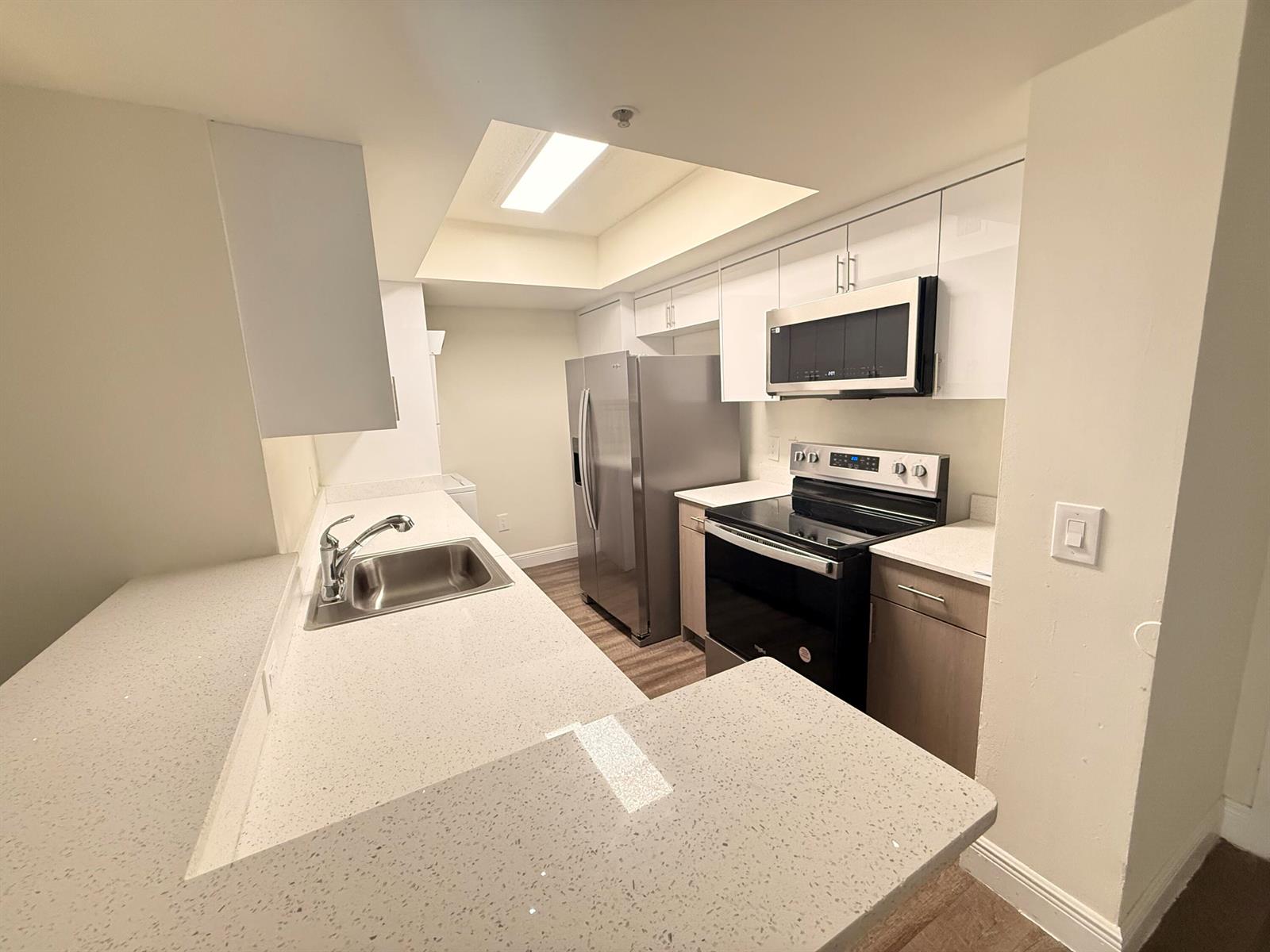 A kitchen features white upper cabinets, light wood lower cabinets, stainless steel appliances, and countertops — 18335 NW 68 Avenue # 420, Hialeah FL 33015, HIALEAH, FL