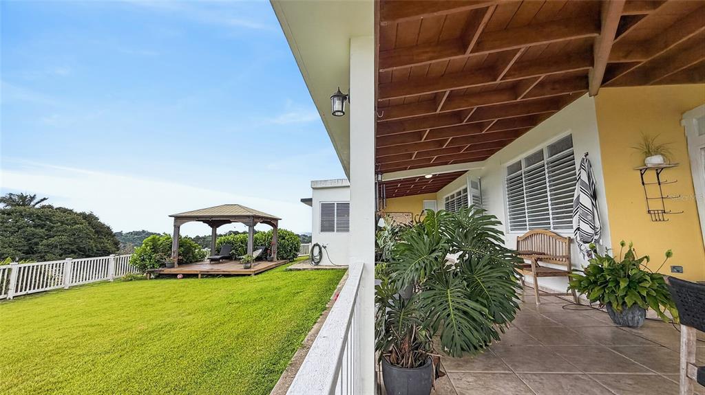 A covered patio with a wooden ceiling overlooks a grassy yard and a wooden gazebo — PR-839 LOT 9, KM 6.7 ALTOS DE CAMARONES, GUAYNABO, PR