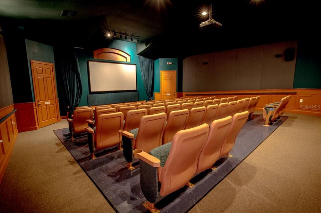 A home theater room features rows of tan seats, a projector screen, and dark walls — 8100 PRINCESS PALM LANE UNIT 203, KISSIMMEE, FL