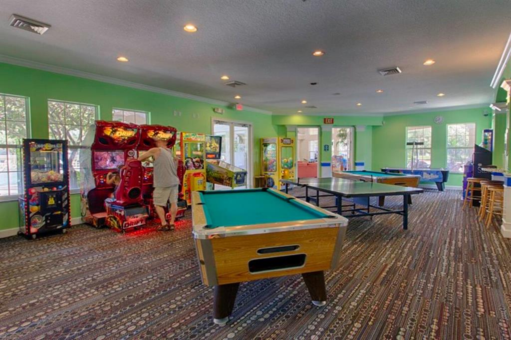 A game room features a pool table, ping pong table, arcade games, and patterned carpeting — 8100 PRINCESS PALM LANE UNIT 203, KISSIMMEE, FL